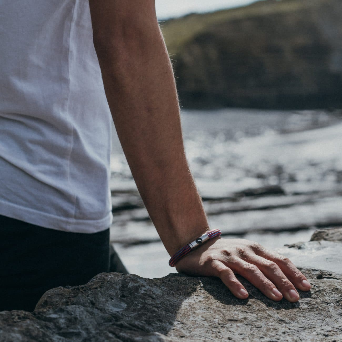 Model wearing blue and red rope bracelet on beach